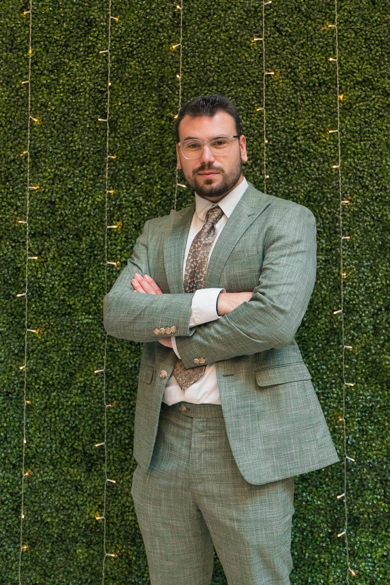 Donny in green suit, arms crossed, green-wall backdrop