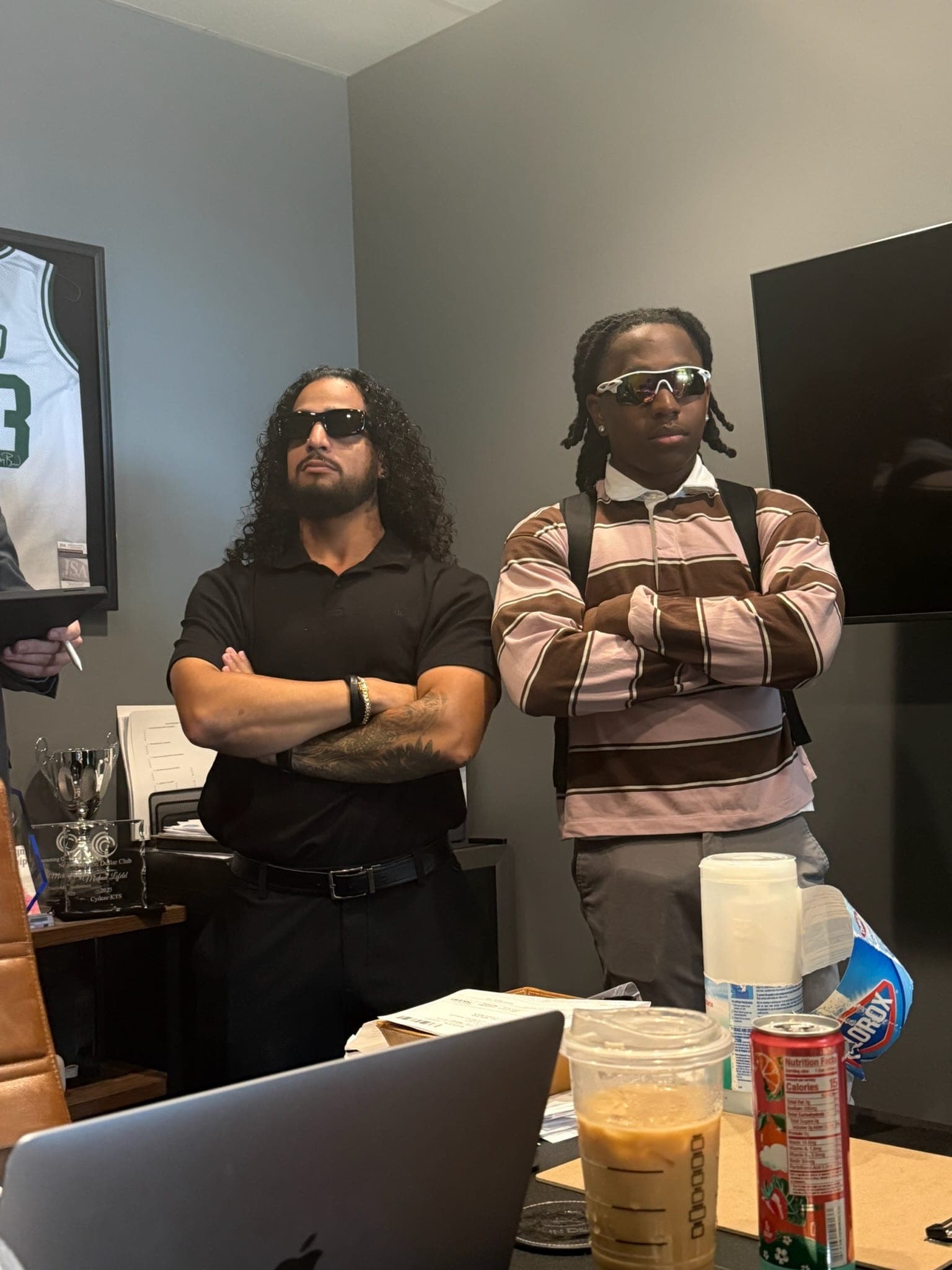 Two team members in sunglasses, arms crossed, in an office