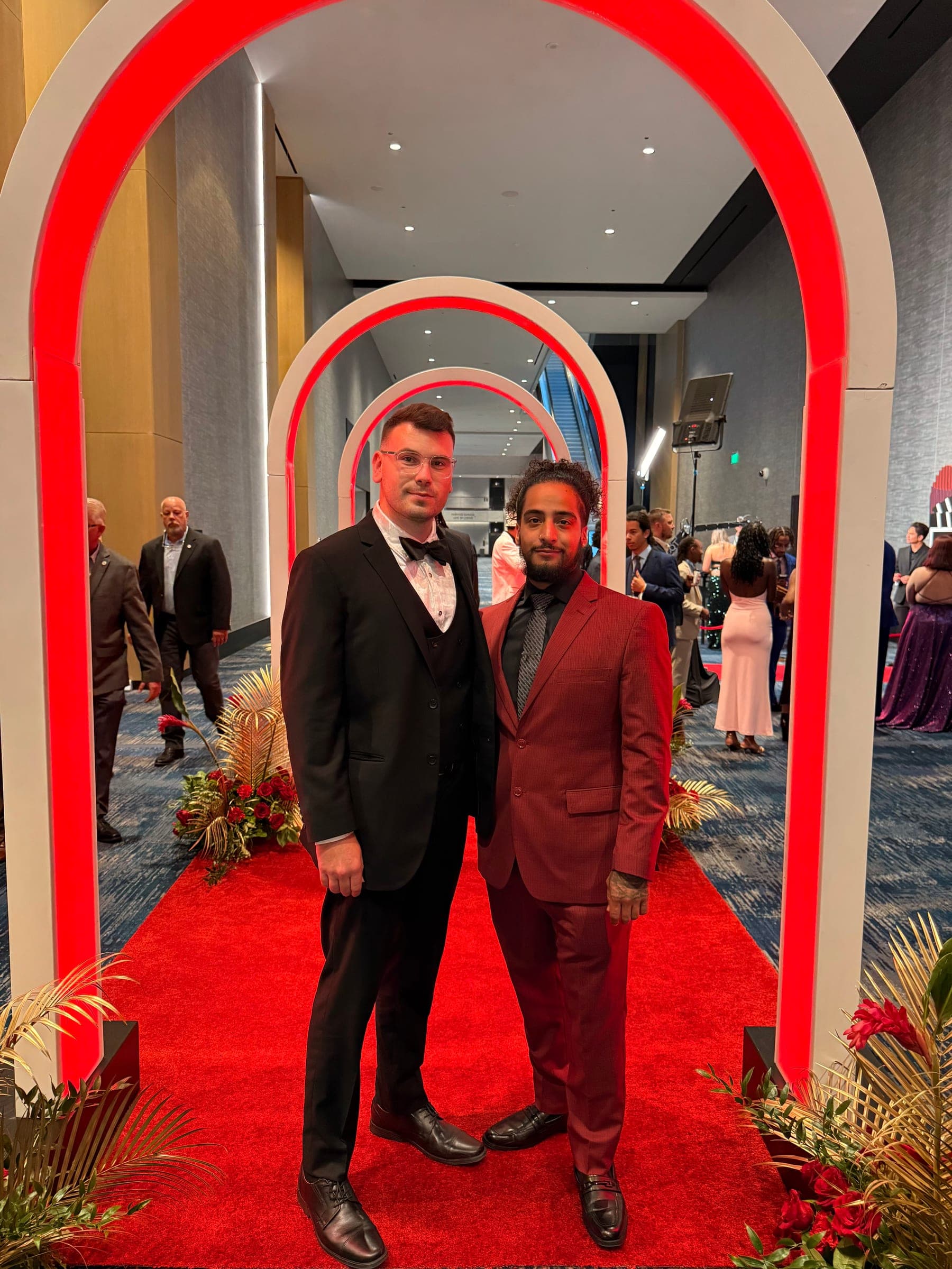 Two team members in formalwear at a gala arch